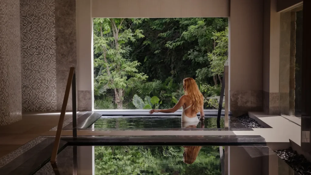 Woman in an indoor plunge pool looking out to tropical forest at Layan Life, Phuket