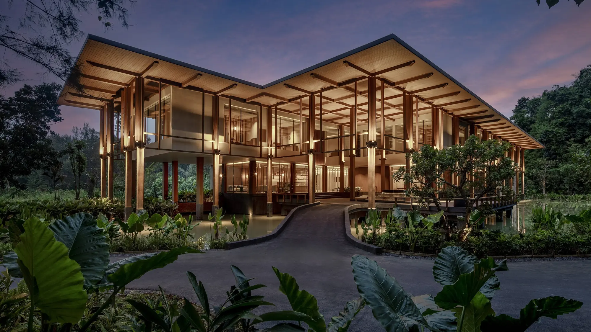 Timber pavilion of Layan Life at Anantara Layan Phuket Resort lit at dusk among tropical gardens