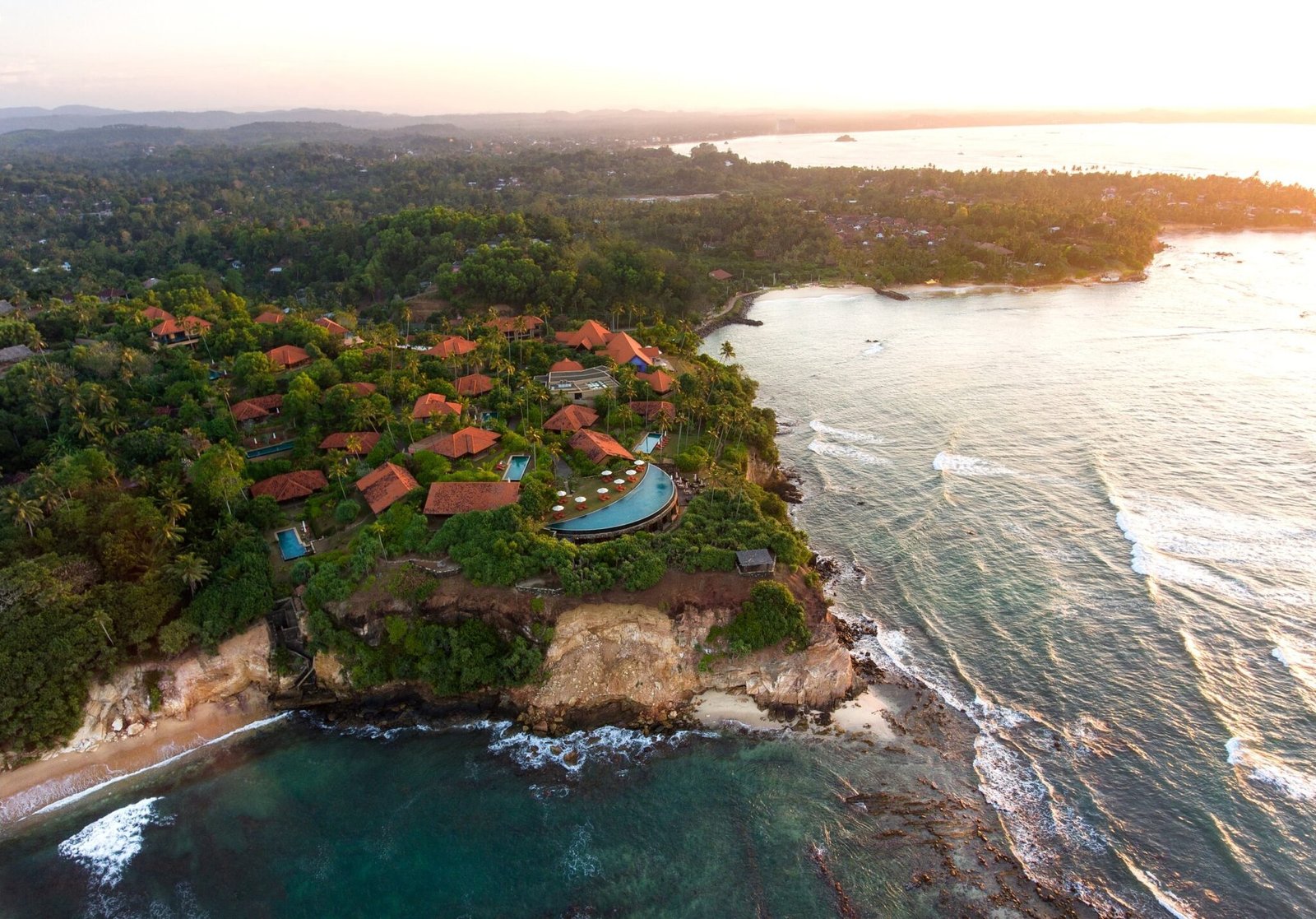 Aerial view of Cape Weligama's clifftop villas and crescent pool above Weligama Bay