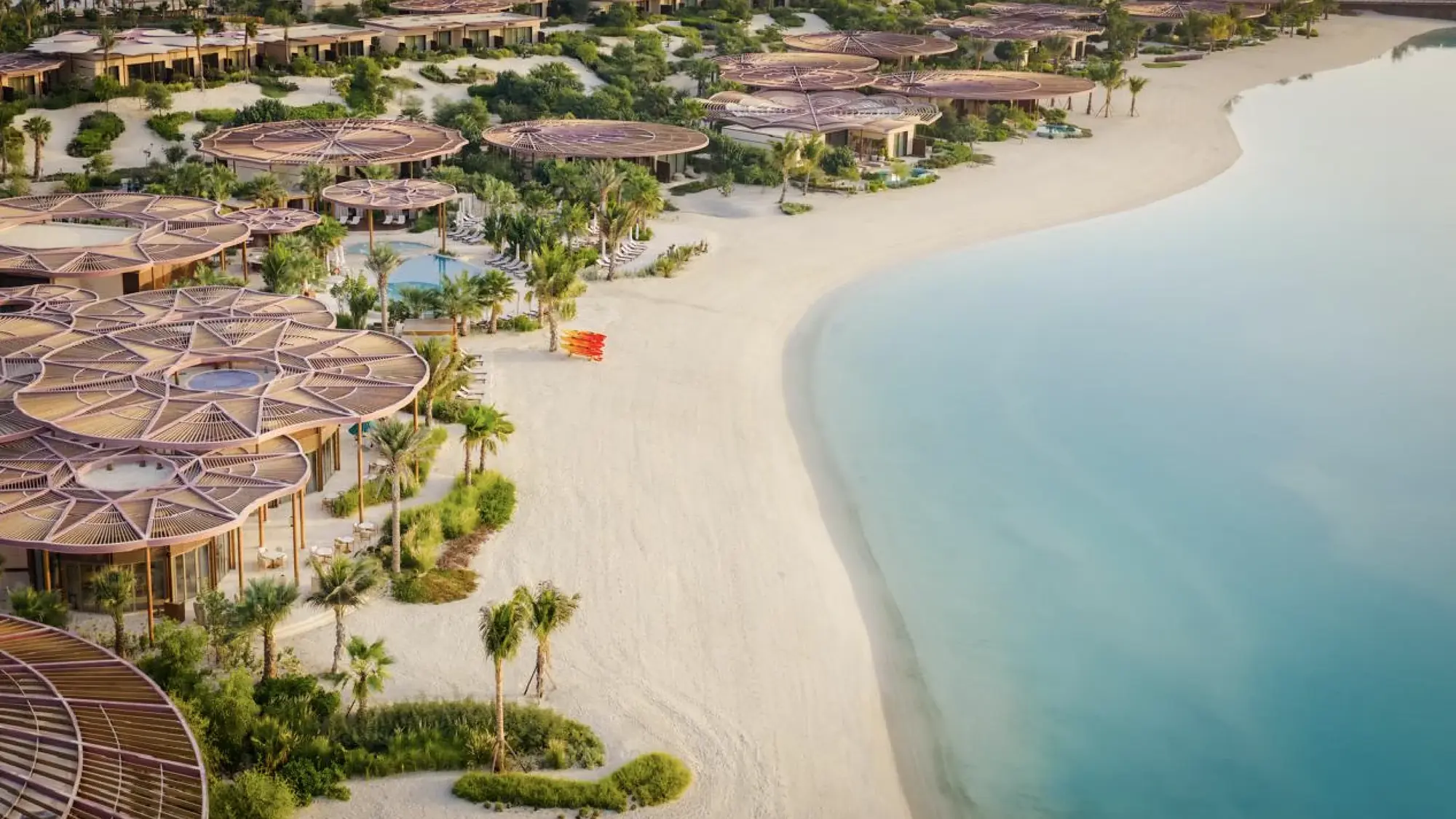 Aerial view of white-sand beach and lagoon lined with villas at Raffles The Red Sea, Shura Island