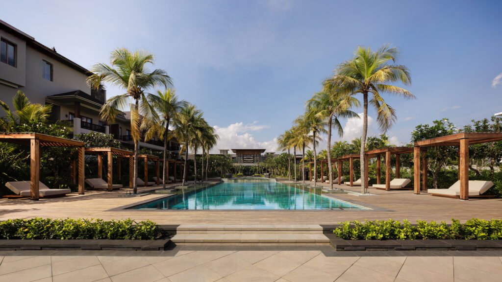 The long main pool at Regent Bali Canggu, lined with palms, pergolas and sun loungers