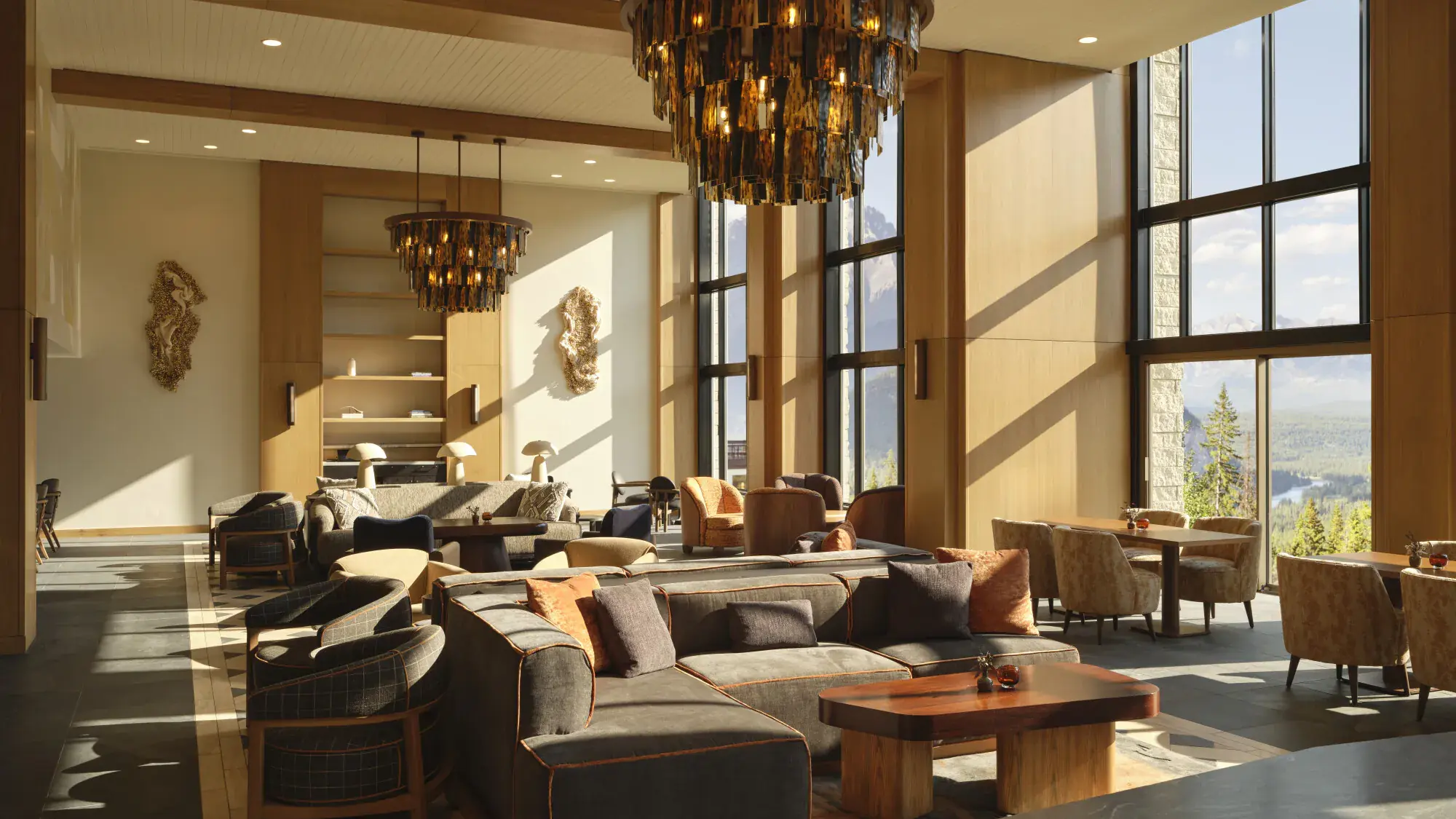 Lobby lounge at Rimrock Banff with chandeliers, sofas and tall windows facing the mountains