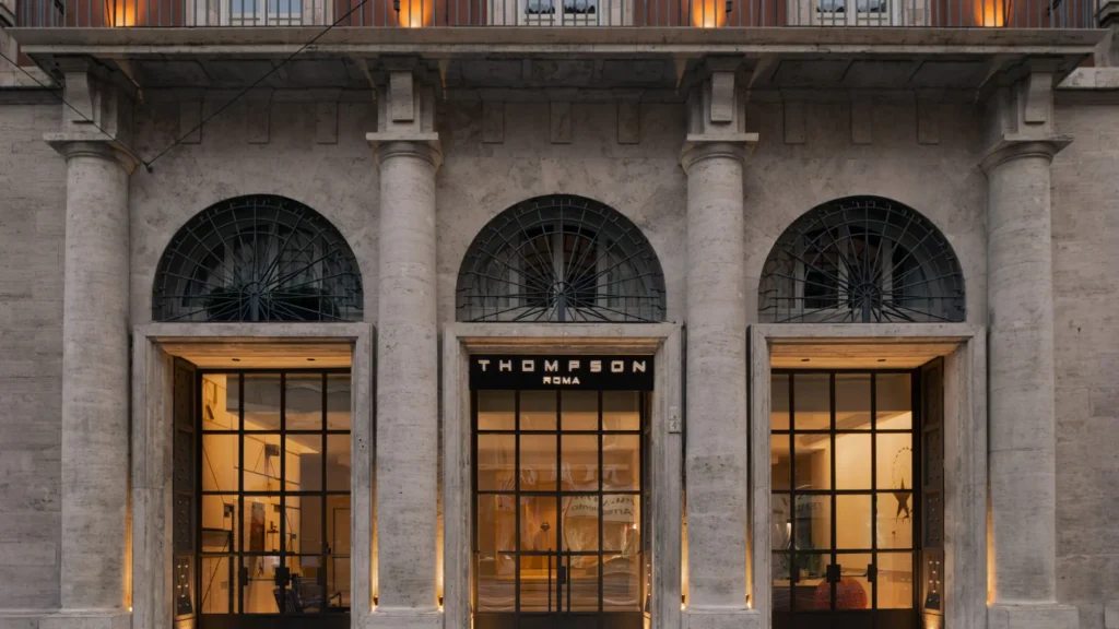 Travertine facade with three arched doorways and the Thompson Roma sign