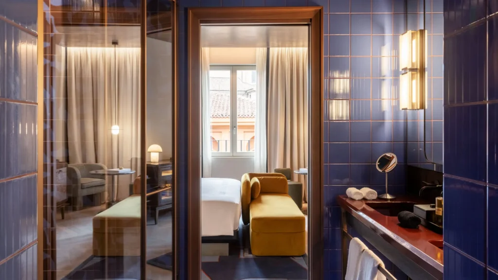Blue-tiled bathroom with a mirrored doorway looking through to a guest room