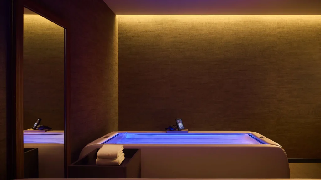 Dimly lit wellness room with a blue-lit treatment bed at Tivoli President Milano