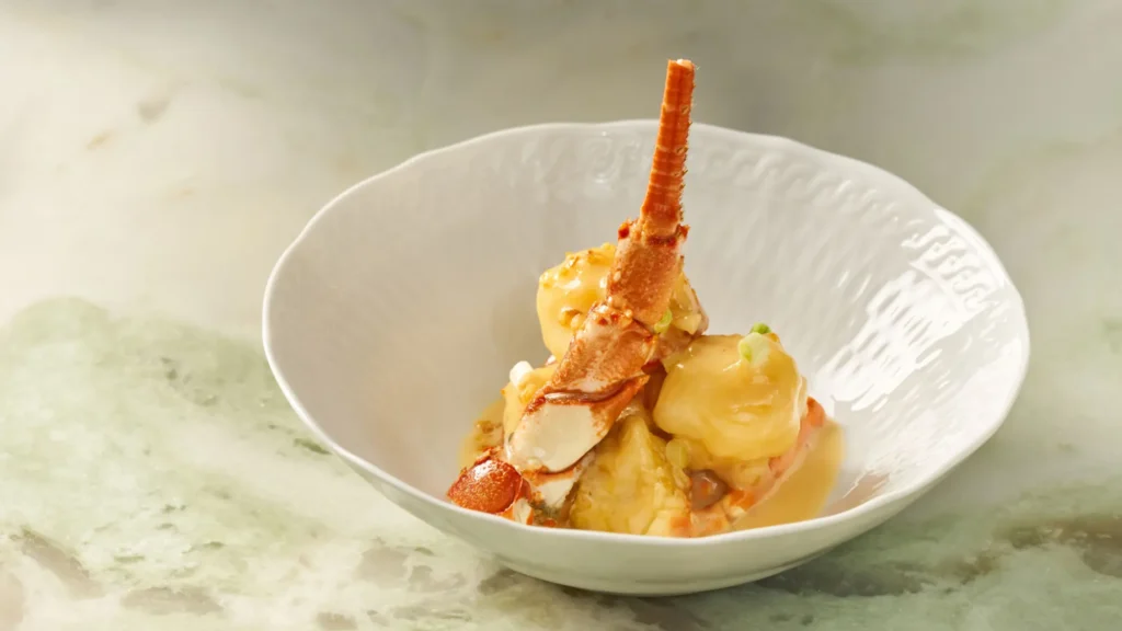 Lobster pieces in a pale cream sauce served in a white embossed bowl